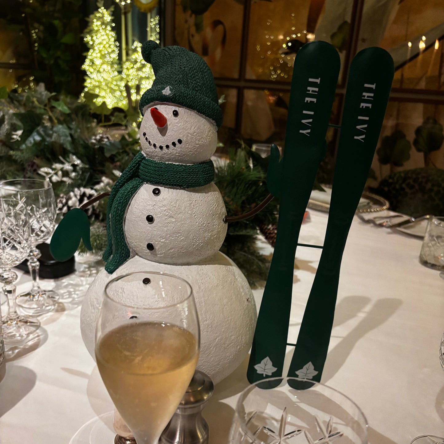 Snowman decoration with a glass of champagne on a festive table setting.