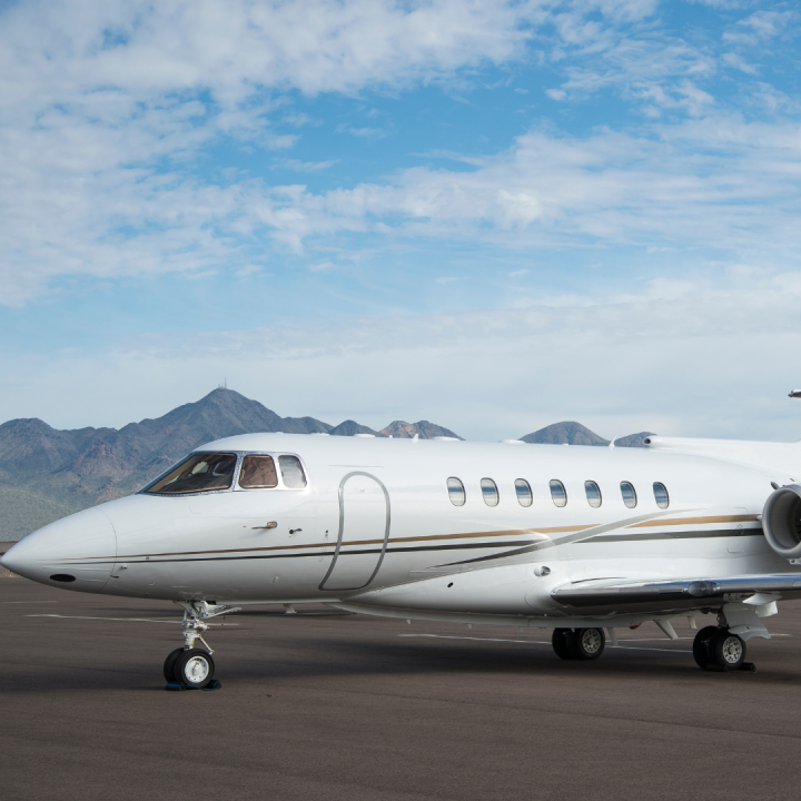 White private jet on a runway with mountains in the background
