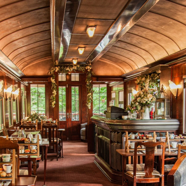 Luxurious train car interior with wooden decor and large windows.